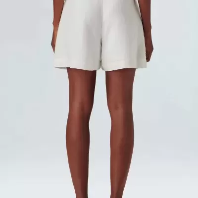 Calções brancos de tecido liso com bainha dobrada e sapatos bege com sola preta