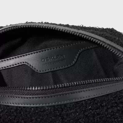 Bolsa preta felpuda com fecho de correr e etiqueta interior de couro com texto OSKLEN RIO DE JANEIRO