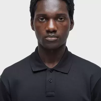 Homem com polo preto de gola e três botões em fundo branco