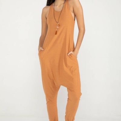 Mulher a usar macacão laranja largo com sandálias castanhas e colar longo