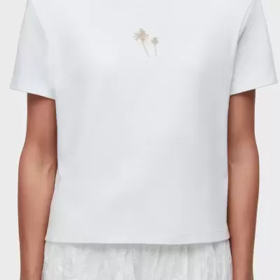 T-shirt branca com palmeiras douradas e saia branca texturizada