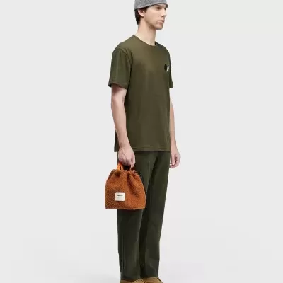 Homem com camiseta verde e gorro cinza, segurando mala castanha de pelo