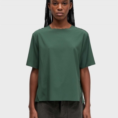 T-shirt verde escura de manga curta e calças pretas com fundo cinza claro