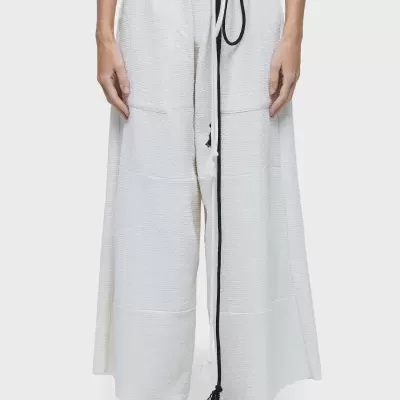 Calças largas brancas com cinturão e cordão preto, usadas com sandálias pretas