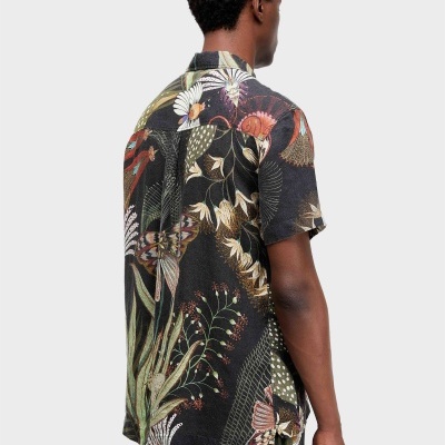 Homem com camisa e calções florais e de folhas, vistos de costas.