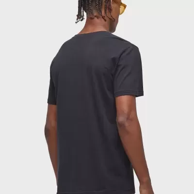 Homem visto de costas a usar t-shirt preta e calças com padrão amarelo e branco