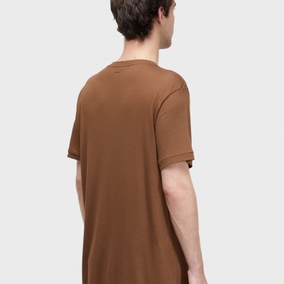 Homem de costas com t-shirt castanha e palavra OSKLEN na parte superior das costas.