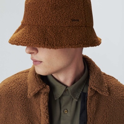 Homem a usar chapéu e casaco castanhos felpudos com camisa verde-oliva.