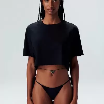 Mulher a usar top preto cropped e cueca de biquíni preta com tiras finas