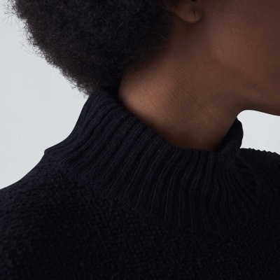 Camisola preta de malha com gola alta em pescoço de pessoa