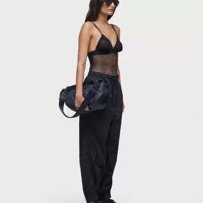 Mulher com roupa desportiva preta e mala desportiva preta em fundo branco