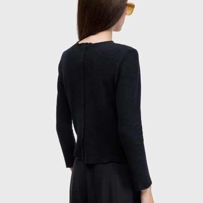 Pessoa de costas com camisola preta de manga comprida, saia preta e óculos de sol amarelos.