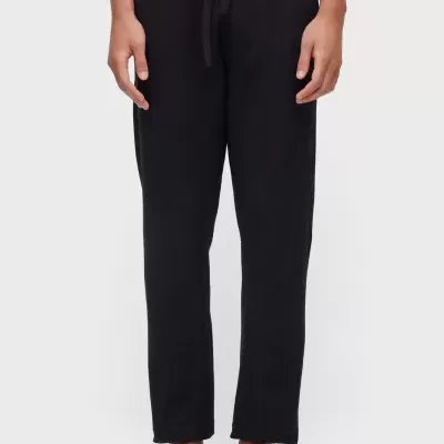 Calças pretas compridas com cordão na cintura em modelo com sandálias pretas.