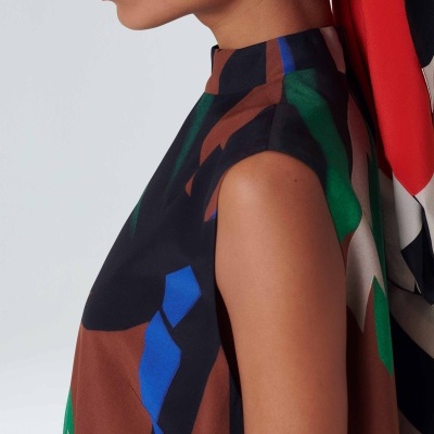 Vestido sem mangas com padrão geométrico colorido em mulher com fundo branco