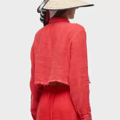 Pessoa de costas com vestido e casaco vermelhos e chapéu de palha com detalhes coloridos