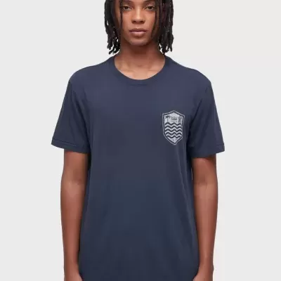 Camiseta azul escura com bolso estampado e calças brancas vista de frente