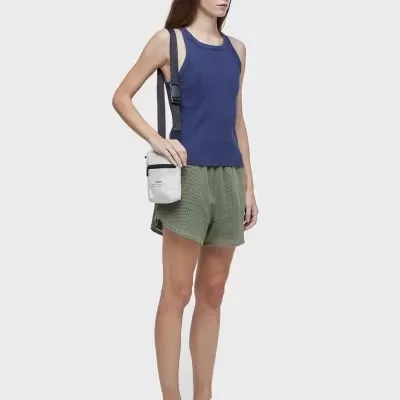 Mulher com roupa casual e bolsa de tiracolo em fundo branco