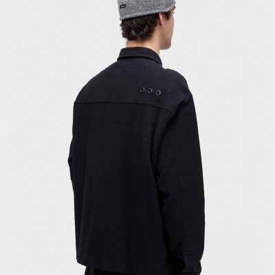 Pessoa de costas com camisola preta de malha e gorro cinzento de malha