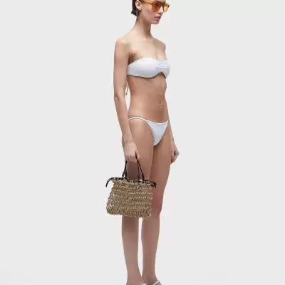 Mulher com biquíni branco, sandálias brancas e carteira de palha