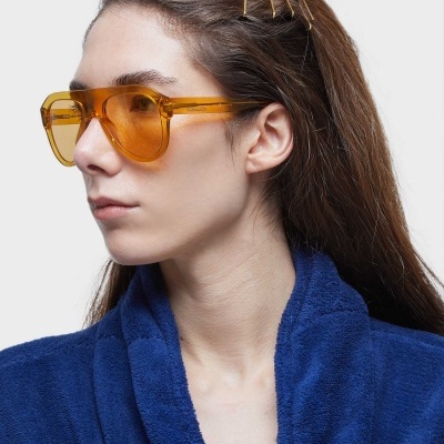 Óculos de sol femininos âmbar hexagonais em mulher com roupão azul