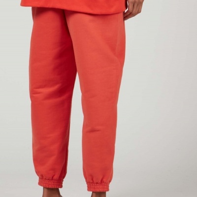 Calças de treino cor de coral com punhos elásticos e chinelos brancos