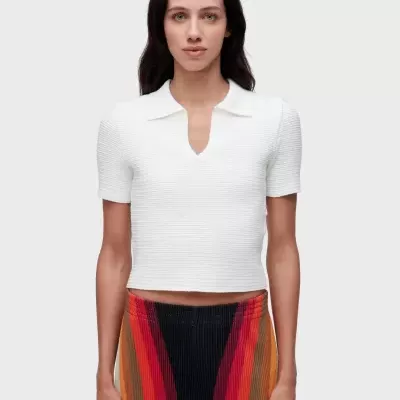 Top branco de manga curta com gola e decote em V e calças plissadas multicoloridas.