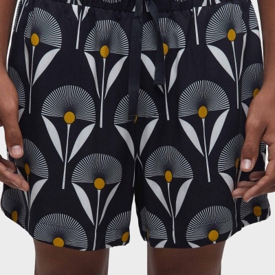 Calções pretos com padrão floral em branco e amarelo, cintura elástica com fita de ajuste.