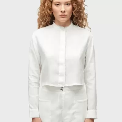 Mulher a usar conjunto branco de camisa e calções com fundo cinzento claro