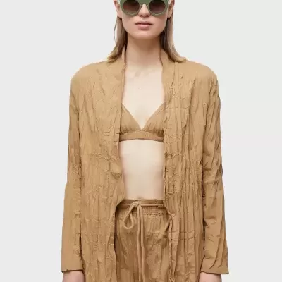 Conjunto feminino bege com blazer, calças e top coordenados, óculos de sol verdes
