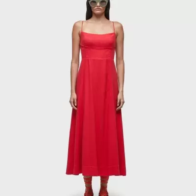 Vestido vermelho longo com alças finas, óculos escuros, meias listradas e ténis cinzentos.