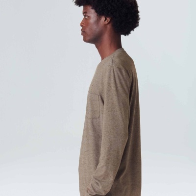 Modelo de perfil com camisola castanha de manga comprida e bolso no peito