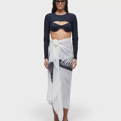 Mulher com top preto, pareo branco e óculos de sol