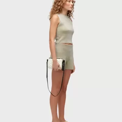 Mulher com conjunto dourado, sandálias e carteira branca padrão escamas.
