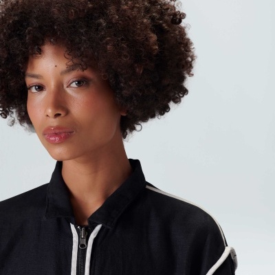 Mulher com casaco preto com fecho branco e detalhes nas mangas