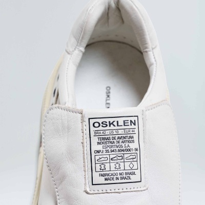 Ténis branco em pele com etiqueta da marca OSKLEN na língua.