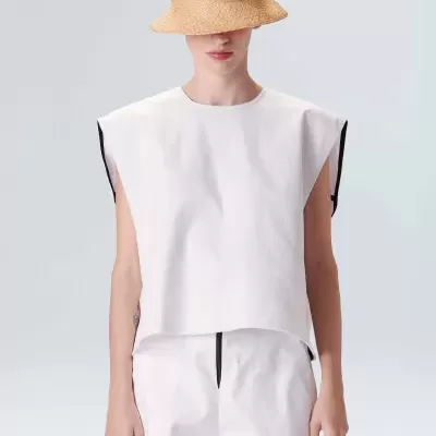 Pessoa com chapéu de palha e roupa branca sobre fundo cinza claro