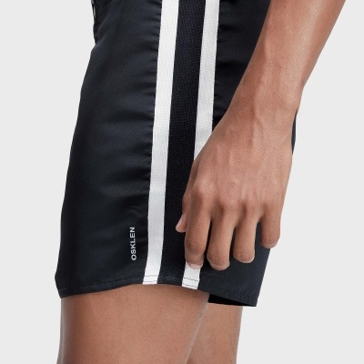 Calções de banho pretos com riscas verticais brancas e pretas, ajuste na cintura e logo OSKLEN numa perna.