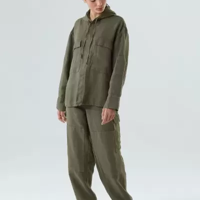 Modelo veste conjunto verde-oliva hoodie com capuz e calças cargo em fundo neutro.