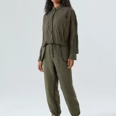 Modelo feminina veste camisa e calças verde-oliva com textura vincada