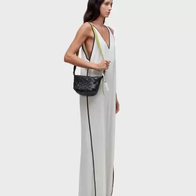 Mulher com vestido branco e mala de ombro preta