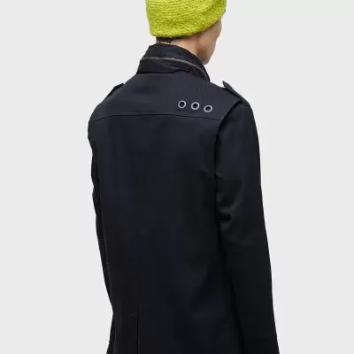 Casaco preto com três ilhós na parte traseira usado por pessoa com gorro verde