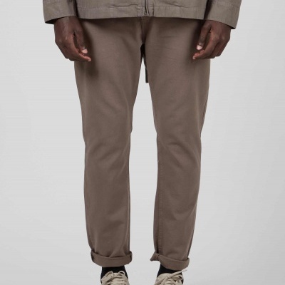 Calças castanhas claras de tecido liso com bainha dobrada usadas com sapatilhas bege