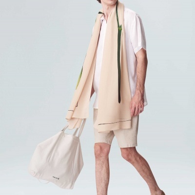 Homem com roupa casual bege e branca segurando mala branca.