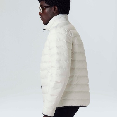 Homem de perfil a usar casaco puffer branco acolchoado, com óculos e calças pretas