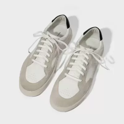 Sapatilhas brancas com detalhes em cinza e preto sobre fundo branco