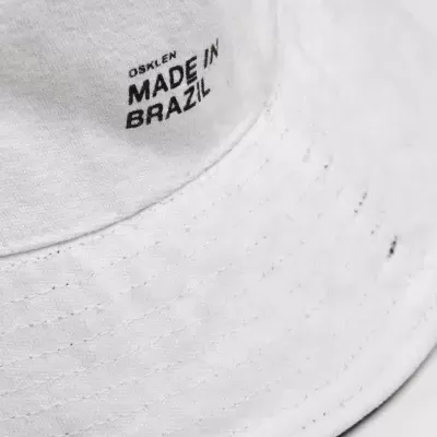 Chapéu branco de tecido com texto preto 'OSKLEN MADE IN BRAZIL'