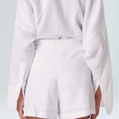 Shorts brancos femininos vistos de costas com camisa branca.
