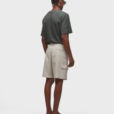 Homem de costas com t-shirt cinza escuro, calções cargo bege e sandálias verdes.