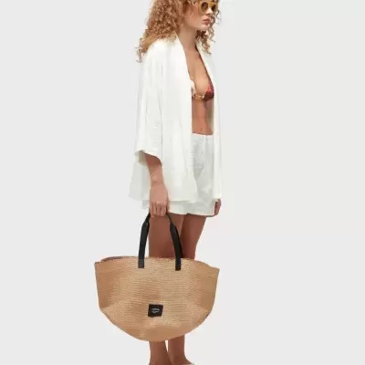 Mulher com roupa de praia branca e bolsa de palha