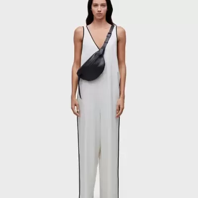 Mulher a usar macacão branco com detalhes pretos e bolsa tiracolo preta